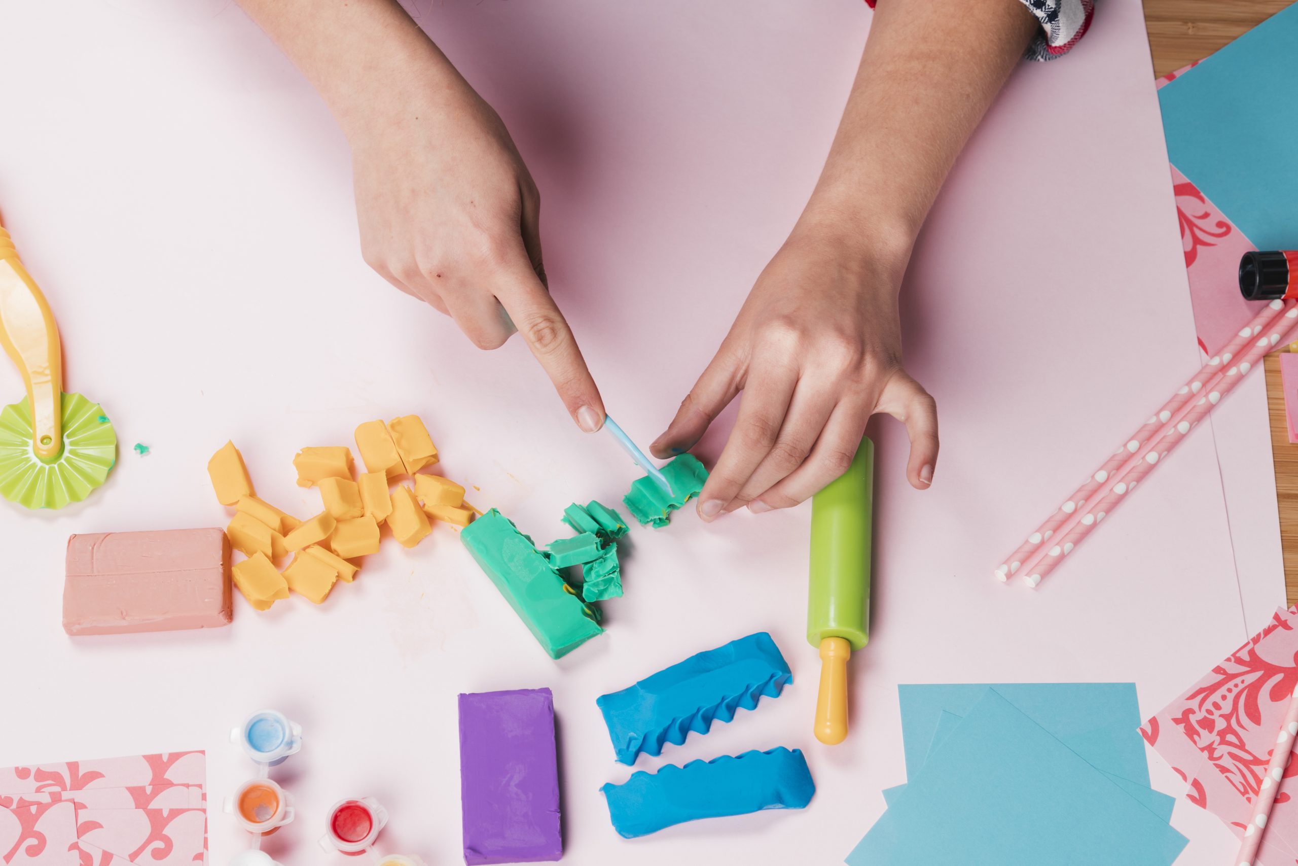 vista de arriba de la mano que corta la arcilla colorida